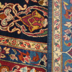 Close detail showing navy, red, and cream scrolling high-pile rug meeting a bright blue geometric woven pattern.