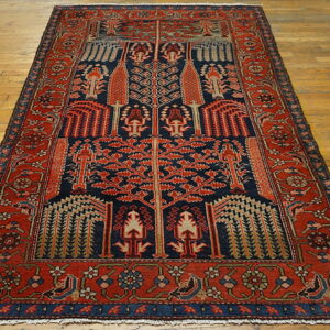 Navy and rust red rug featuring a detailed geometric Tree of Life pattern rests on light hardwood flooring.
