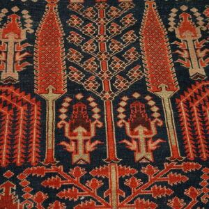 Detailed view of a low-pile rug with intricate red and cream geometric patterns on a dark navy blue background.