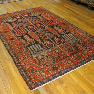 Detailed traditional rug in red-orange and navy blue on a glossy wooden floor.