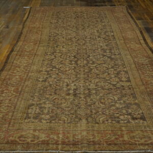 Faded long runner with dark floral motifs and wide beige borders rests on distressed wood planks.