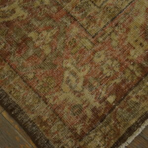 Low-pile rug featuring distressed patterns in gold, olive, and rust over dark wooden planks.
