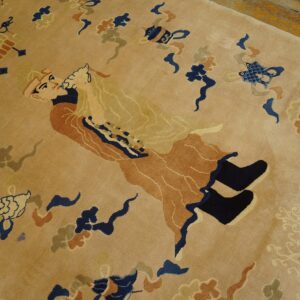 Plush tan rug with detailed navy and rust figurative and geometric patterns on a wood floor.