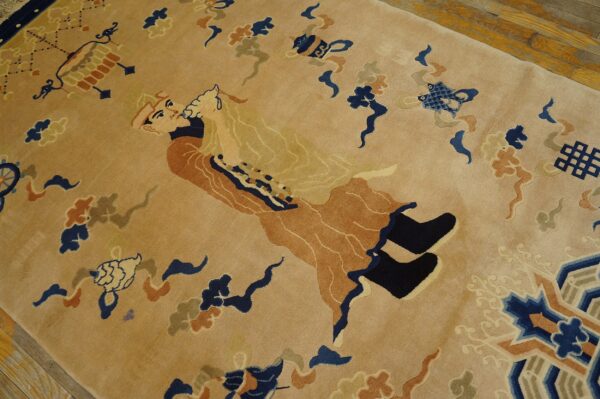 Plush tan rug with detailed navy and rust figurative and geometric patterns on a wood floor.