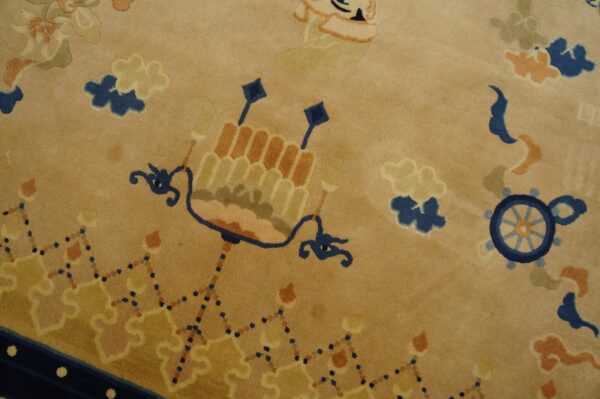Close-up of a low pile tan rug with stylized blue, orange, and gold traditional patterns.