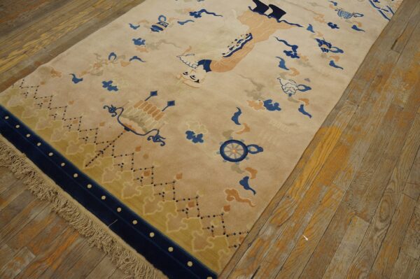 A plush tan rug with blue, peach, and yellow stylized motifs lies on distressed wide-plank wood flooring.