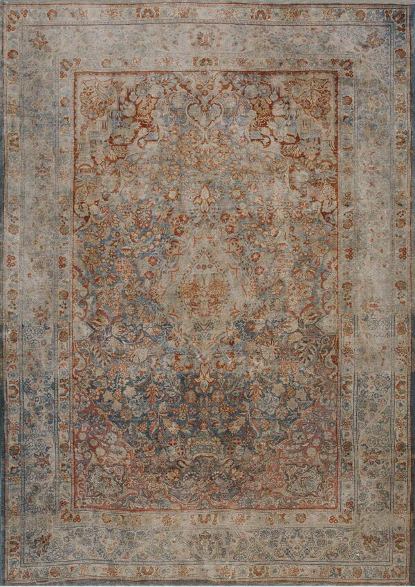 Distressed rug with an ornate floral pattern in muted blue, rust, and tan tones.