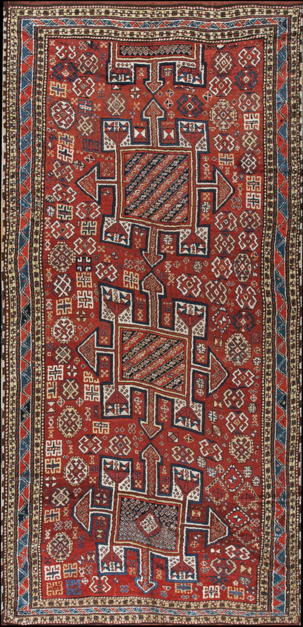 A vertical red rug featuring large geometric blue and cream medallions and dense tribal motifs.