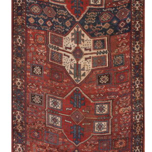 Intricate red rug with large geometric motifs and central medallions colored navy blue and cream.
