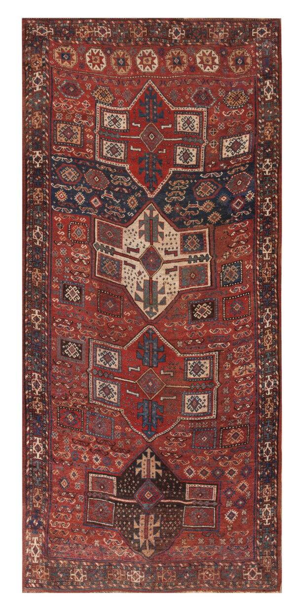 Intricate red rug with large geometric motifs and central medallions colored navy blue and cream.