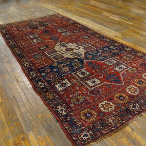 Red and navy geometric patterned rug with low pile on a distressed wooden floor.