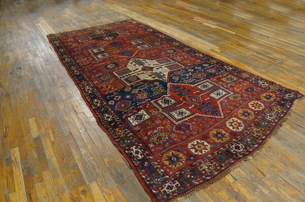 Red and navy geometric patterned rug with low pile on a distressed wooden floor.