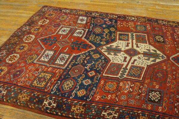 Geometric rug with rust, navy, and cream medallions lies diagonally on a honey-toned wood floor.
