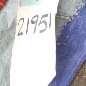 Close-up of a textured red rug edge next to a white tag marked with the number 21951.