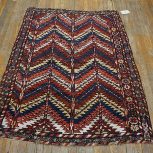 Low pile rug with large red, navy, tan, and white geometric zig-zags on distressed wooden planks.