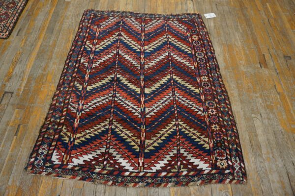 Low pile rug with large red, navy, tan, and white geometric zig-zags on distressed wooden planks.