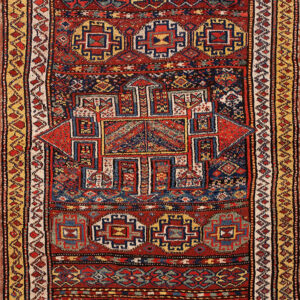 Red geometric rug with a central medallion and complex borders in navy blue, cream, and mustard yellow.