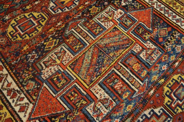 Densely patterned rug detail featuring geometric blocks of red, navy blue, yellow, and cream colors.