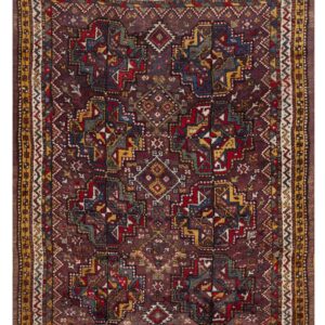 Deeply saturated geometric rug featuring a dark red field with complex patterns in gold, blue, and cream.