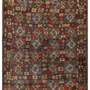 A richly colored rug with a geometric grid pattern using deep red, blue, yellow, and brown tones.