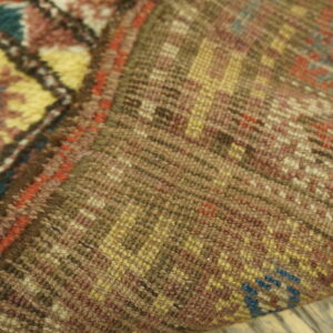 The high-pile face with yellow and blue diamonds is contrasted with the flat, brown woven backing texture.