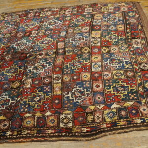 A high-pile rug featuring a colorful geometric grid pattern in red, blue, yellow, and green on rustic wood floors.
