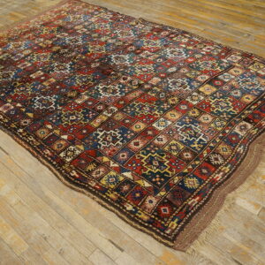 A richly colored, low-pile rug with intricate red, blue, and yellow diamond motifs on rustic wood floors.