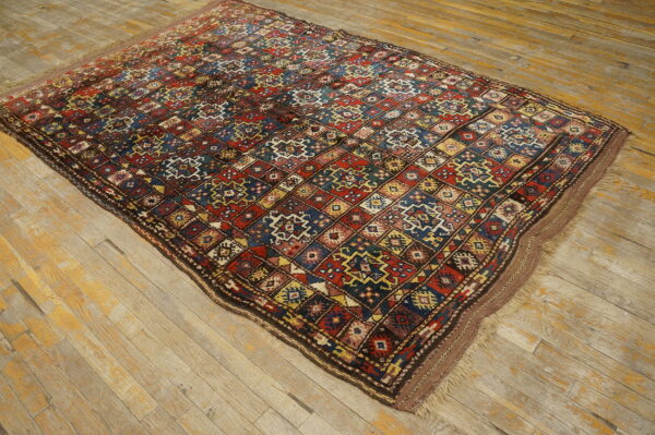 A richly colored, low-pile rug with intricate red, blue, and yellow diamond motifs on rustic wood floors.