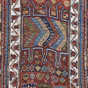 Reddish-brown rug featuring complex geometric patterns, zigzag stripes, and detailed borders in navy, cream, and green.