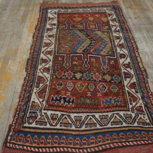 Red, blue, and ivory geometric pattern rug with low pile lies on distressed wooden floorboards.