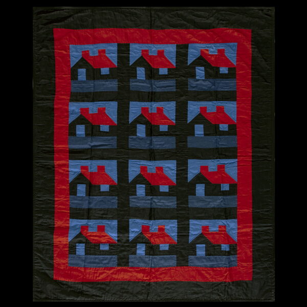 Black quilted textile featuring a repeating pattern of red-roofed houses against blue and black squares.