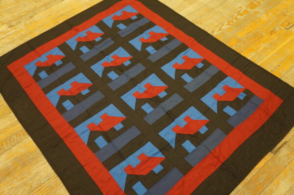 Red, blue, and dark brown flat textile with a bold geometric grid pattern resting on bright wood floors.