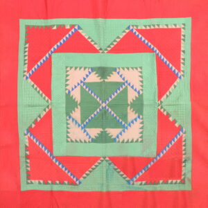 A vibrant textile rug with concentric geometric borders and sawtooth designs in coral red and shades of green.