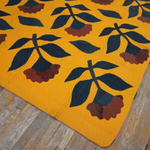 Gold flat-weave rug featuring large blue and maroon floral patterns covers distressed gray wooden flooring.