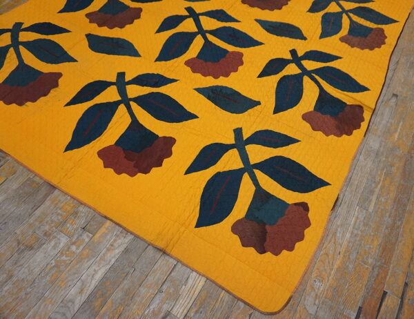 Gold flat-weave rug featuring large blue and maroon floral patterns covers distressed gray wooden flooring.
