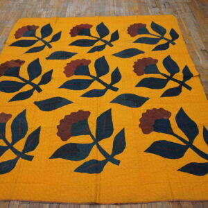 Mustard textile featuring large dark teal and maroon floral patterns rests on distressed wood planks.