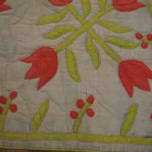 A quilted textile featuring appliquéd red tulips and green stems on a pale blue background.