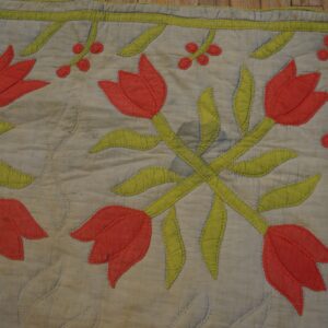 Flat appliquéd rug with red tulips and lime green foliage on a quilted gray background.
