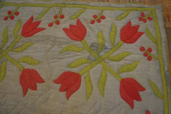 Flat appliquéd rug with red tulips and lime green foliage on a quilted gray background.
