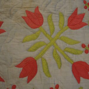Appliqued red tulips and green stems on a quilted blue textile resting on wooden planks.