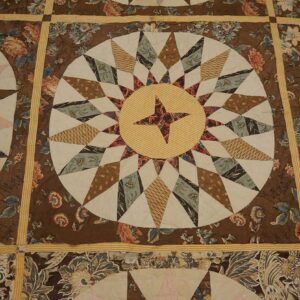 Brown, cream, and yellow textile featuring radiating star medallions framed by dark floral print blocks.