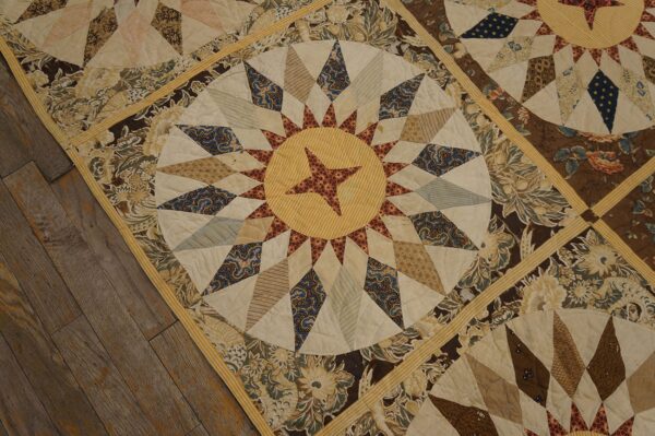 Patchwork textile featuring circular sunburst patterns and floral borders in cream, brown, and blue on wood floors.