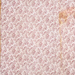 Cream rug with a repeating pattern of mauve grape bunches and leaves on a visible hardwood floor.