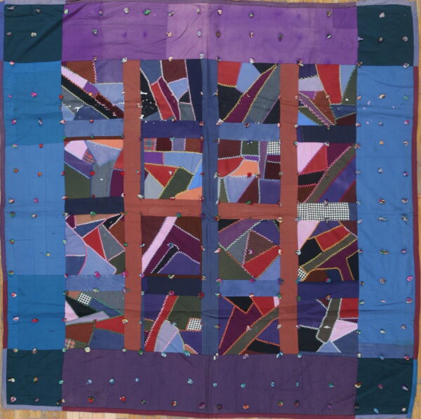 Square textile with crazy quilt patchwork squares framed by purple and blue borders with scattered knots.