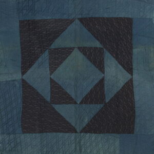 Quilted textile with a geometric pattern in dark indigo blue and black, featuring detailed stitchwork texture.