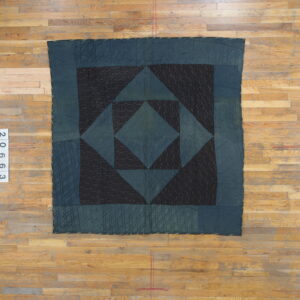 Quilted dark blue and black geometric rug featuring squares and triangles on light plank hardwood flooring.