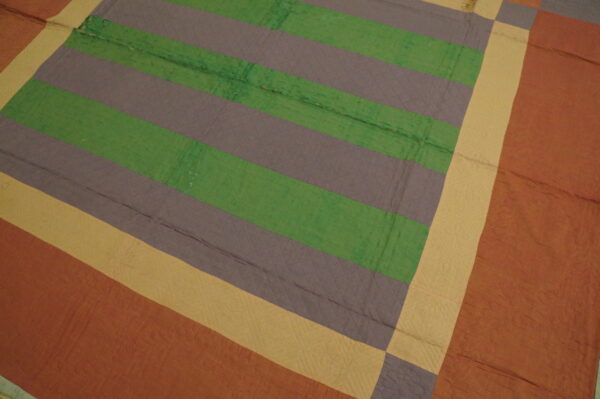 Quilted textile featuring wide horizontal stripes in green and grayish-purple, framed by yellow and rust borders.