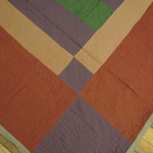 Low-pile rug with diagonal geometric sections in rust, purple, tan, and green on plank wood flooring.