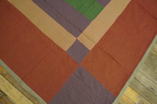 Low-pile rug with diagonal geometric sections in rust, purple, tan, and green on plank wood flooring.