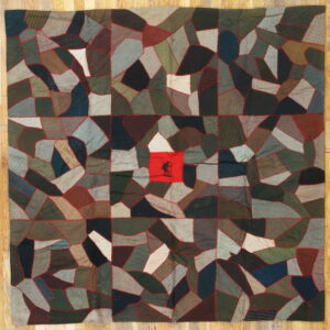 Flat textile rug with irregular dark patches and red stitching; a central red square features a black silhouette.